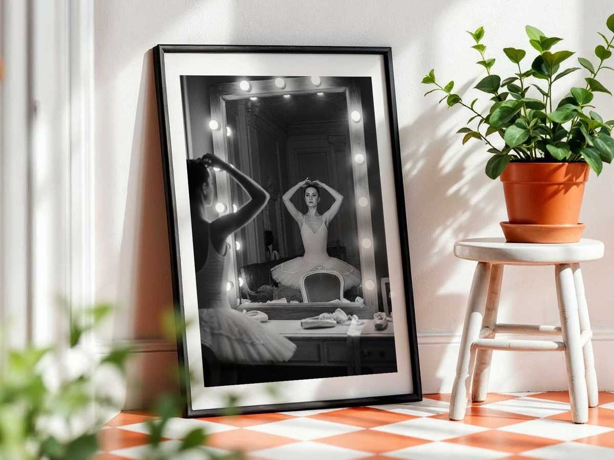 Wide-angle view of a rehearsal where a dancer composes a complex gesture, the mirror doubling the composition and enriching…