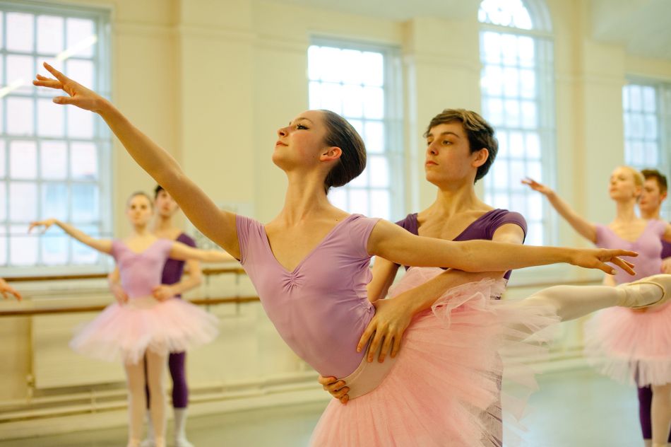 Principal soloist practicing an intricate variation with coach and pianist in the rehearsal studio