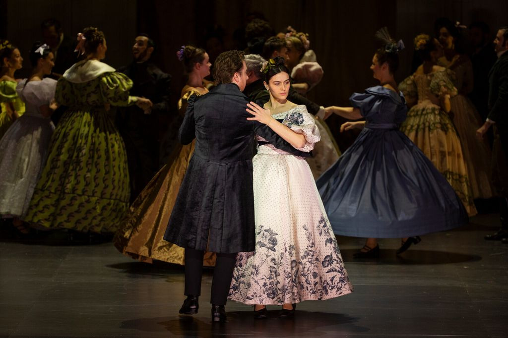 Full company performing the formal ball scene from Onegin with period costumes and stylized group formations