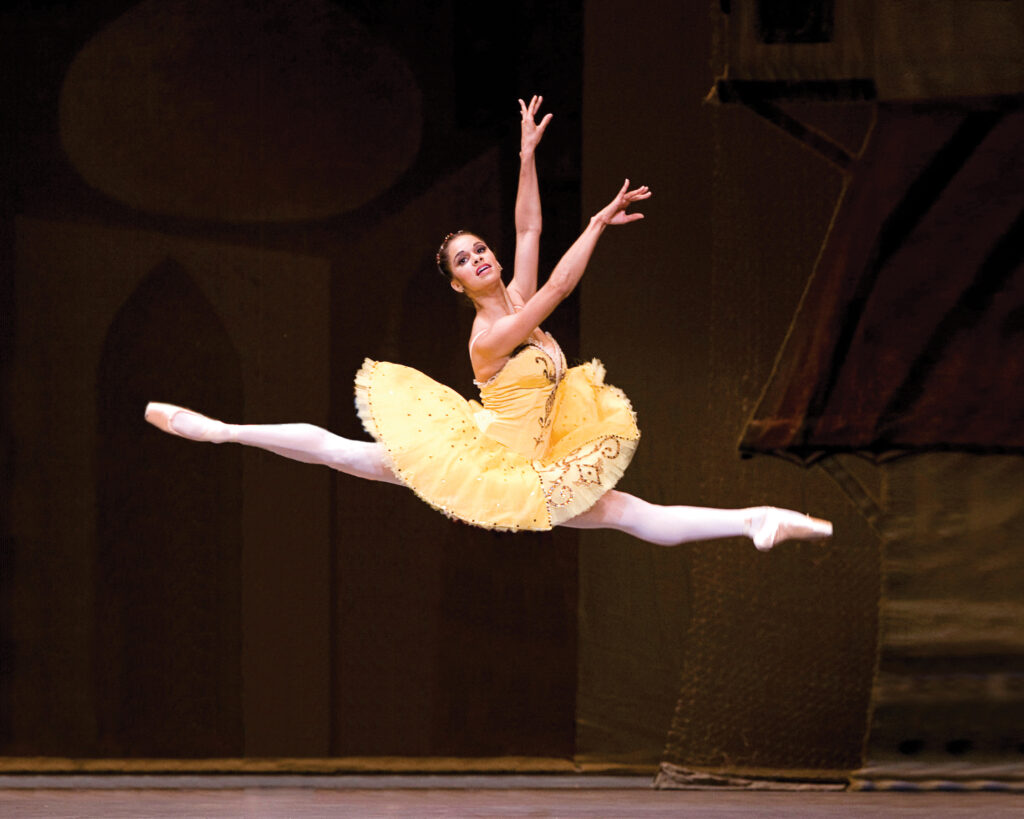 Misty Copeland suspended mid-leap in a sparse studio, body creating a dynamic negative space