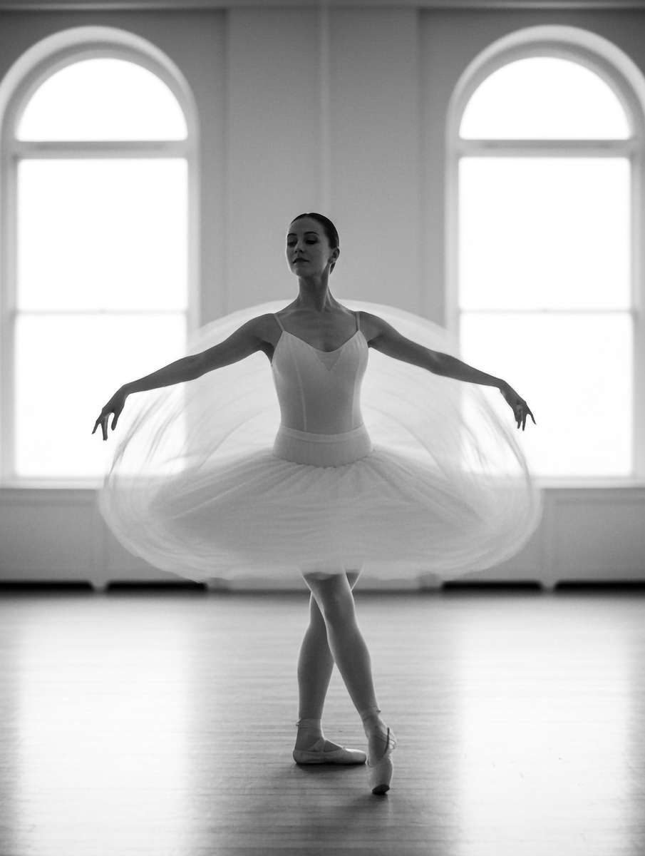 Dancer practicing in front of a studio mirror, silhouette and reflection emphasizing the construction of a pose during a…