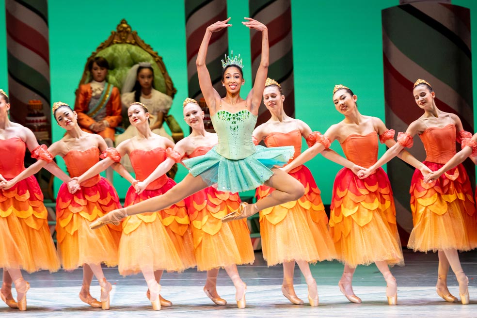Principal dancer in a neoclassical pose against a minimalist set, showing Balanchine-influenced technique