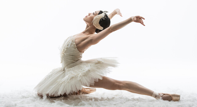 Odile in a black tutu executing a dramatic pas de deux with the prince on a grand theater stage