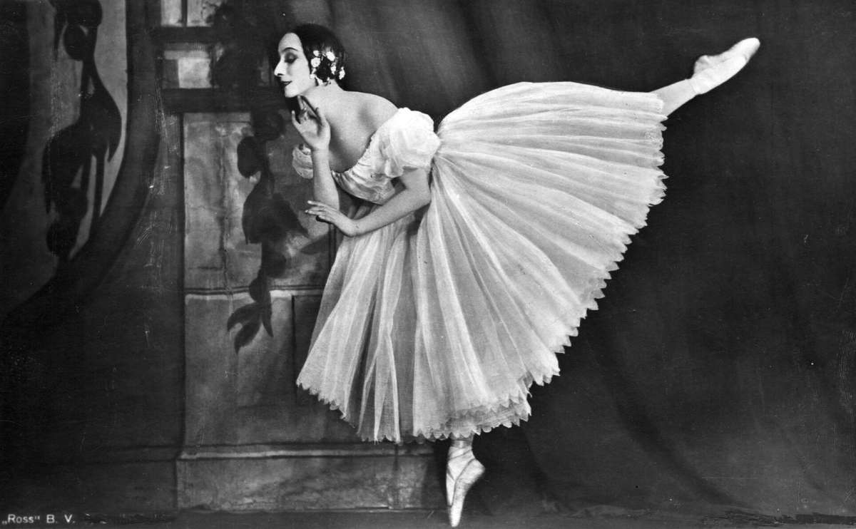Anna Pavlova performing The Dying Swan onstage, arms curved like a swan's wings, expressive face turned upward